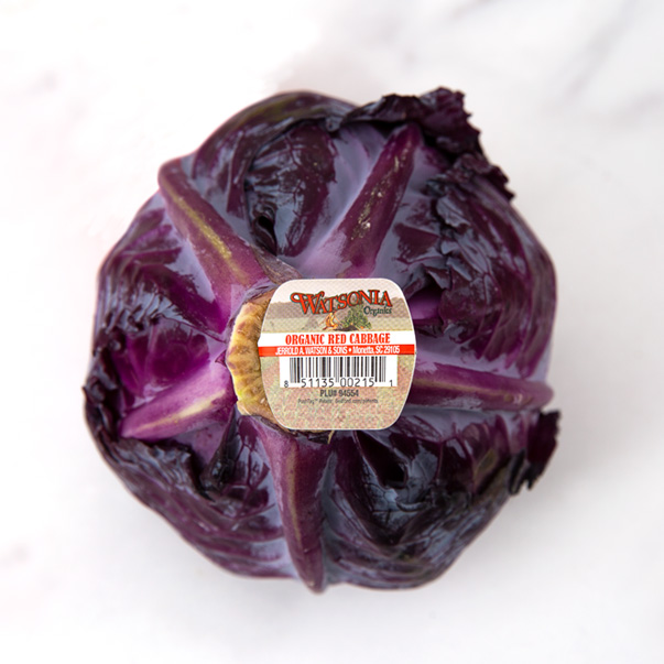 A produce butt tag inserted into the end of a Watsonia brand organic red cabbage.