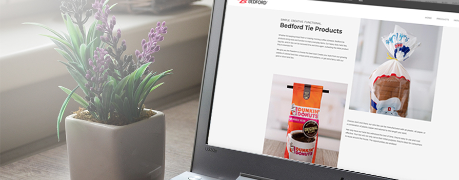 A laptop screen shows a "Bedford Tie Products" webpage with product images. A potted plant is nearby. The Bedford logo is in the corner.