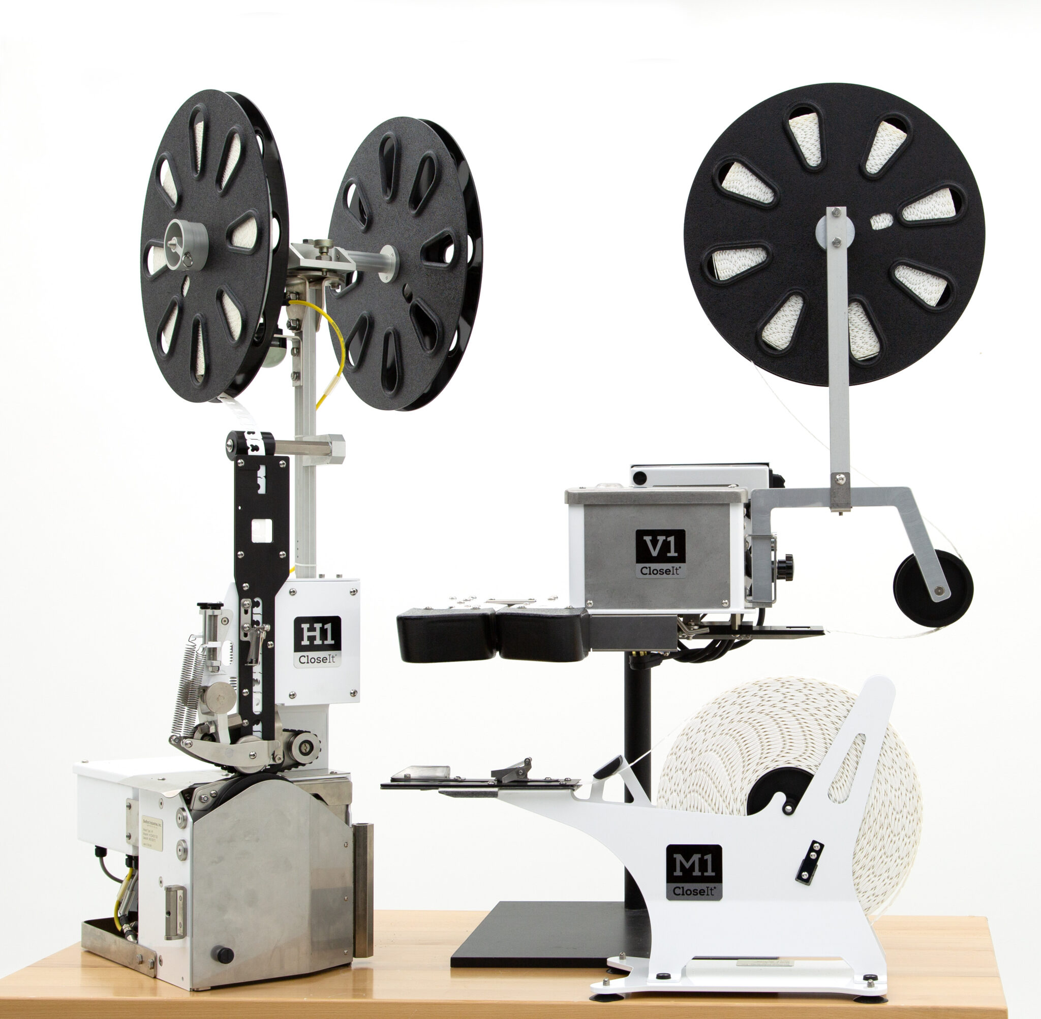 3 bag closure machines with reels of closet bag clips attached.