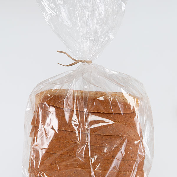 a tan, Kraft paper recycled twist tie closing a loaf of white bread.