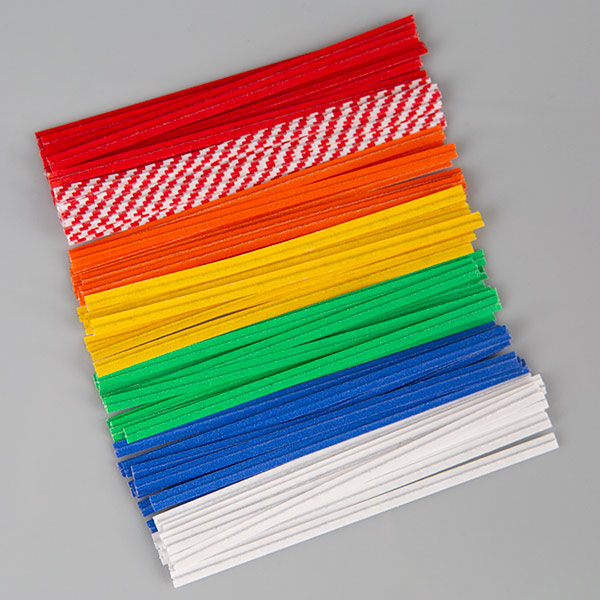 A stack of colorful Bedford twist ties arranged in rows on a gray background. The twist ties are grouped by color, including red, red-and-white checkered, orange, yellow, green, blue, and white.