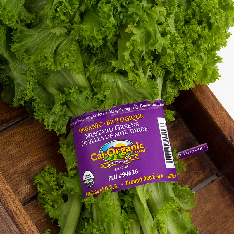 A purple Cal-Organic branded produce Bib Tie around a bunch of mustard greens.