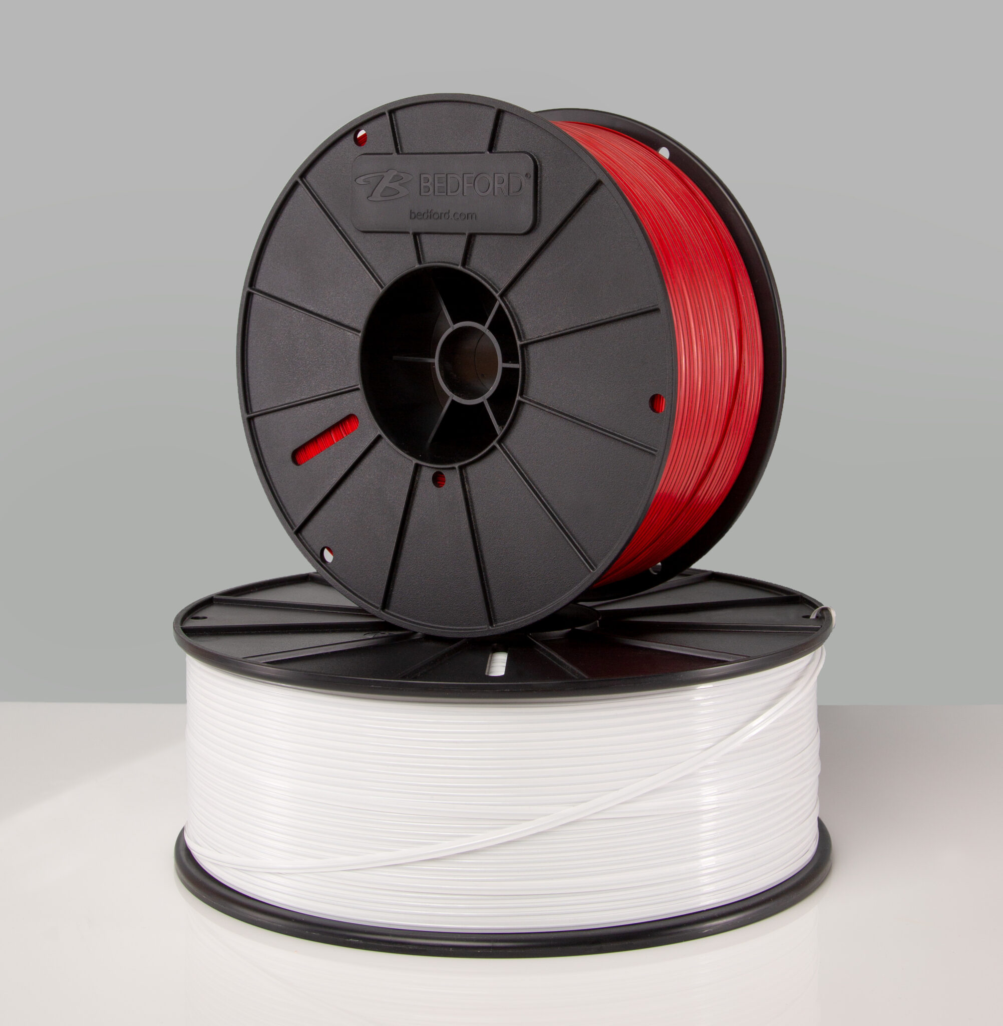 Two spools of twist ties, one red and one white, stacked on top of the other with "Bedford.com" logo on the red spool.