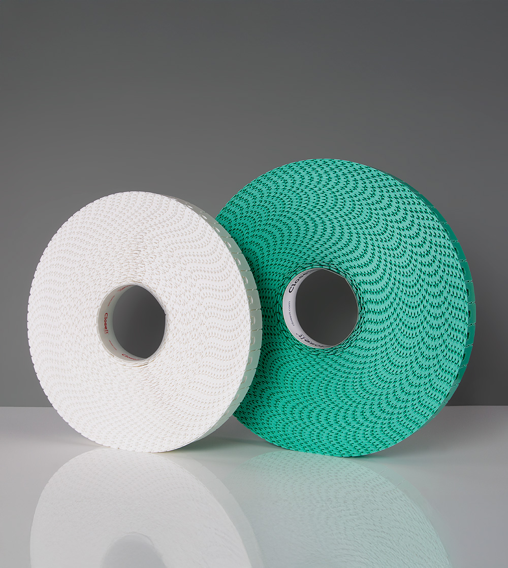 Two spools of CloseIt bag closures side by side, one white, and one larger green.