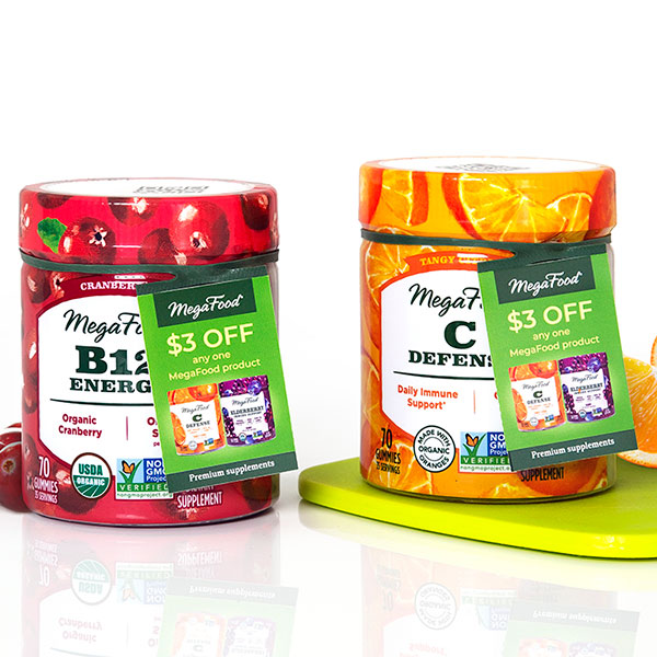 MegaFood B12 Energy and C Defend gummies with $3 off ElastiTag hangtags. Cranberry and orange flavors, on a green surface.