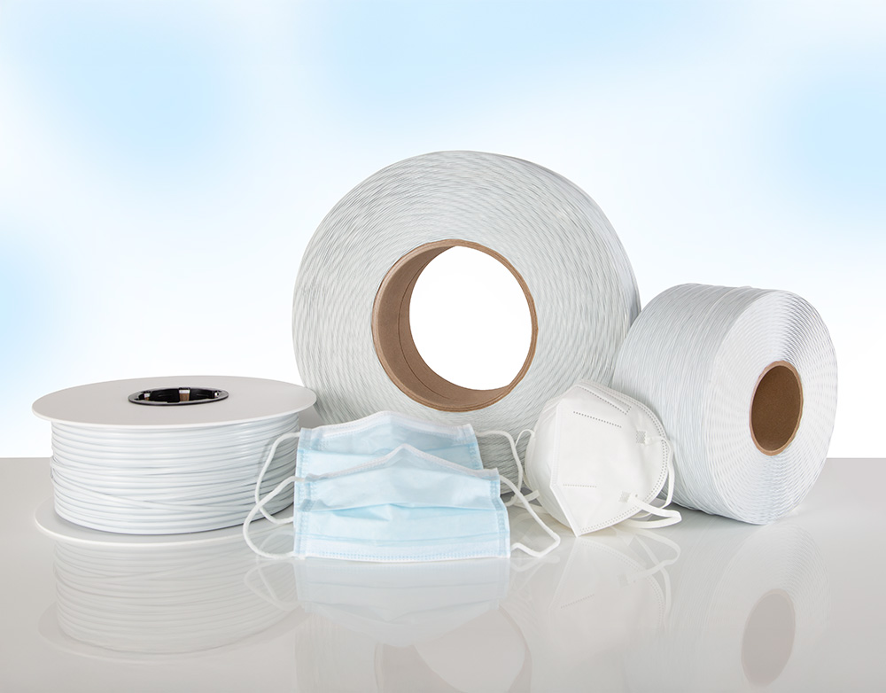 White, plastic-coated medical wire wound on 3 spools and 3 medical face masks with face mask nose wire in front.