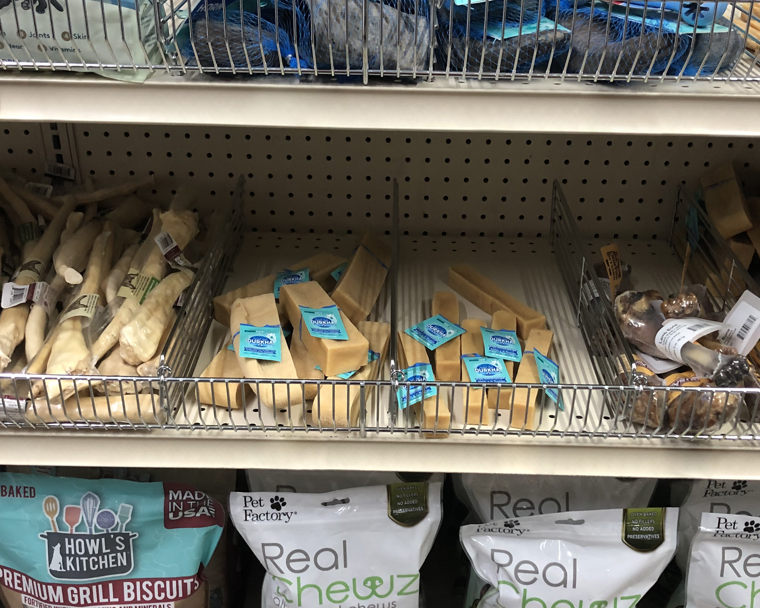 A variety of dog bones and treats on a store shelf. The dog bones have teal ElastiTags as pet treat labels.