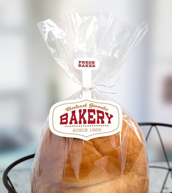 Loaf of bread in clear plastic bag with "Fresh Baked" and "Baked Goods Bakery Since 1966" tag attached to the bag by a white twist tie.