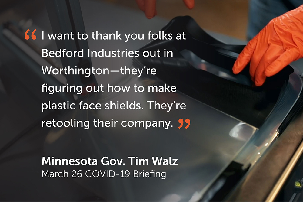 Orange-gloved hands grab a stack of face shields in background of quote ""I want to thank you folks at Bedford Industries out in Worthington – they're figuring out how to make plastic face shields. They're retooling their company." - Minnesota Gov. Tim Walz, March 26 Covid-18 Briefing."