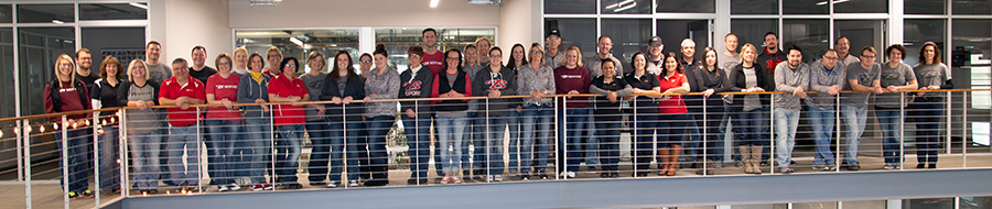 A large group of people with Bedford shirts on in front of a long railing.