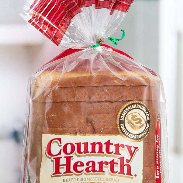A green printed twist tie closing a loaf of Country Hearth branded bread. The tie has "MON" printed on it to signify the day it was made.
