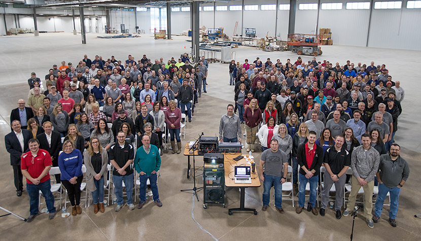 A large group of Bedford Employees pose for a photo in a newly built addition to our manufacturing facility