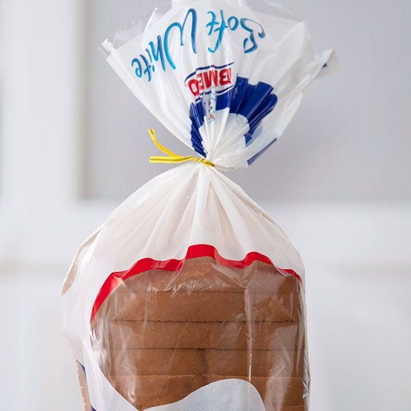 A yellow bread tie on a white bread bag.