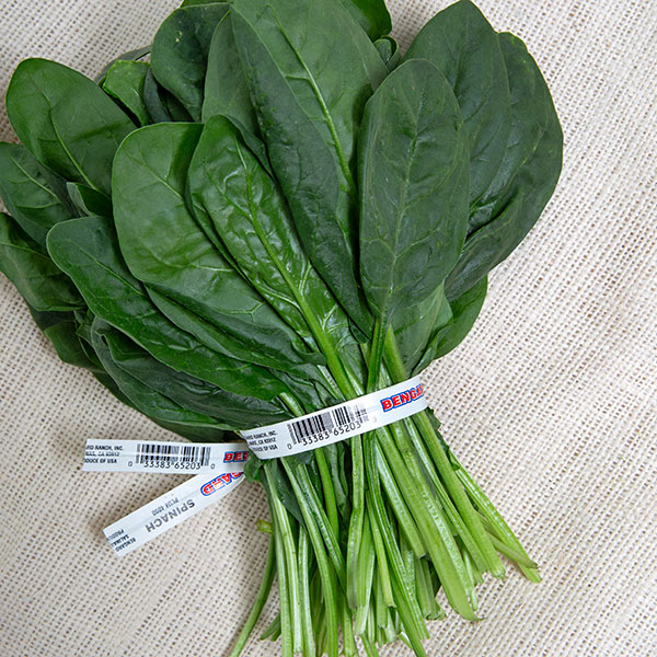 A bunch of fresh, dark green spinach leaves tied together with a barcode label.