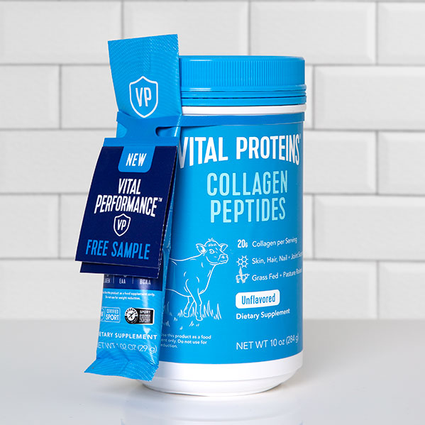 A blue container of Vital Proteins Collagen Peptides with a smaller packet of a free sample attached with an ElastiTag tote. The container is on a white tiled background.